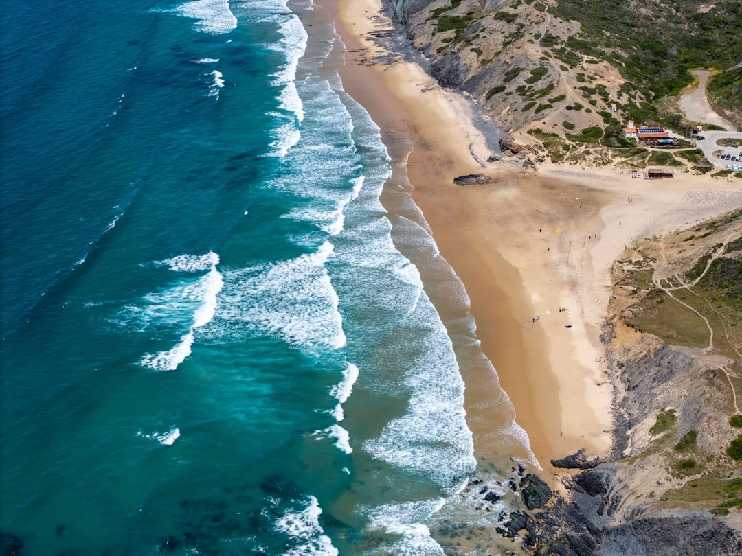 Aerial view of a rugged Atlantic coastline with turquoise water and golden sand at sunset